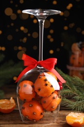 Christmas composition with tangerine pomander balls in wineglass on wooden table
