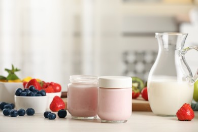 Portion jars for yogurt maker and different fruits on white wooden table in kitchen