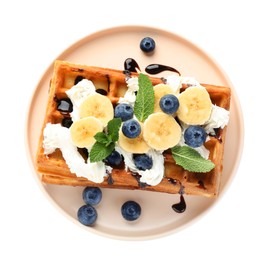 Photo of Plate of delicious Belgian waffles with blueberry, banana, whipped cream and chocolate sauce isolated on white, top view