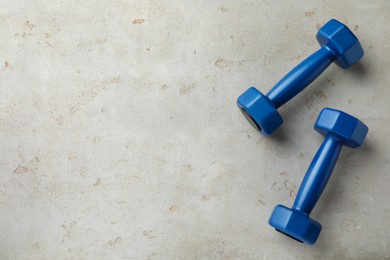 Blue dumbbells on light grey table, flat lay. Space for text