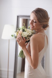 Photo of Bride in beautiful wedding dress with bouquet indoors