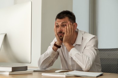 Photo of Sleep deprived man at workplace in office