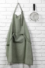 Photo of Clean kitchen apron with pattern and sieve on white brick wall