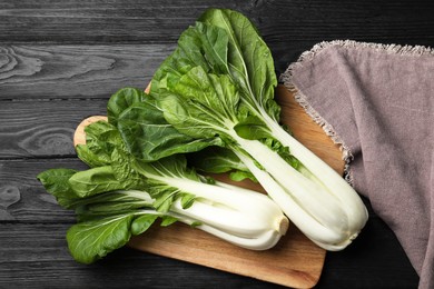 Fresh green pak choy cabbages on black wooden table, top view