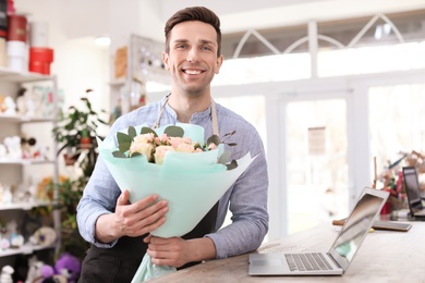 Male florist holding bouquet flowers at workplace