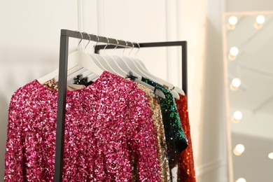 Photo of Clothing rack with colorful sequin party dresses on hangers in boutique