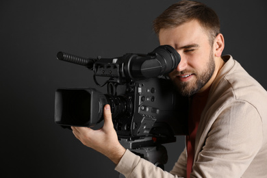 Operator with professional video camera on black background