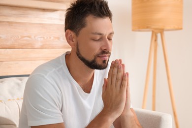 Photo of Religious man with clasped hands praying indoors