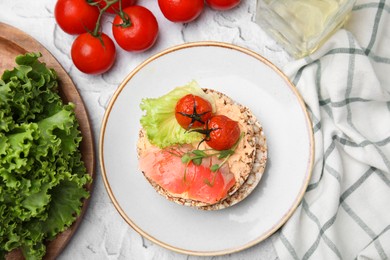 Crunchy buckwheat cakes with salmon, tomatoes and greens on white table, flat lay