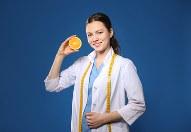 Nutritionist with ripe orange on blue background