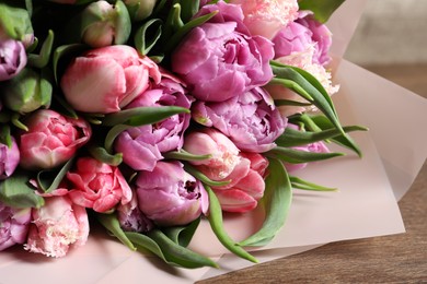 Photo of Bouquet of beautiful tulips on wooden table, closeup