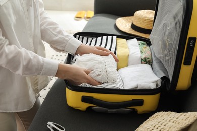 Woman packing suitcase for trip in living room, closeup