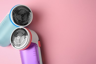 Photo of Modern fabric shavers on pink background, flat lay. Space for text