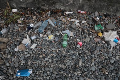 Photo of Garbage scattered on pebbles outdoors. Recycling problem