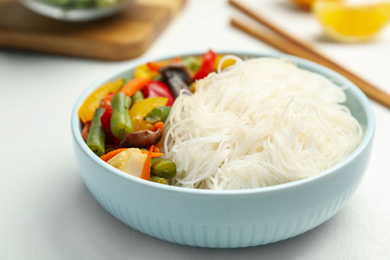 Tasty cooked rice noodles with vegetables on white table