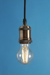 Hanging modern lamp bulb against blue background