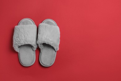 Pair of soft fluffy slippers on red background, top view. Space for text