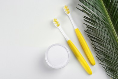 Photo of Toothbrushes and bowl of baking soda on beige background, flat lay. Space for text