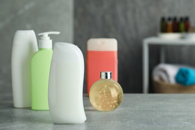 Bottles of shower gel on grey table in bathroom, space for text