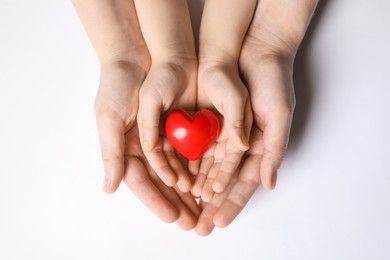 Woman and kid holding red heart in hands on white background, top view