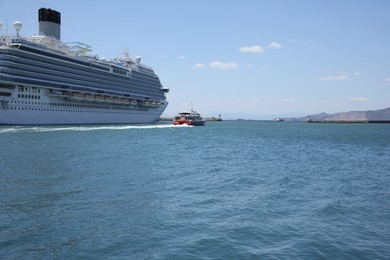 Modern cruise ship and boat in sea on sunny day
