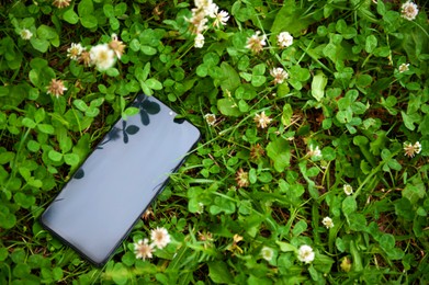 Smartphone on green grass outdoors, space for text. Lost and found