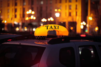 Photo of Taxi car with yellow checkered sign on city street in evening