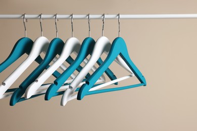 Clothes hangers on metal rail against beige background