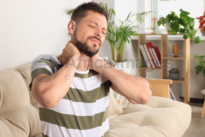 Photo of Man suffering from neck pain in room