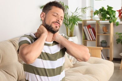 Man suffering from neck pain in room