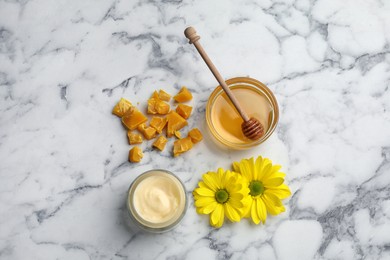 Natural beeswax, cream, honey and flowers on white marble table, flat lay