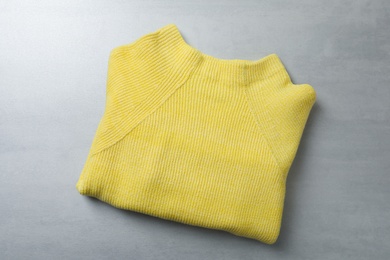 Photo of Yellow warm sweater on light grey table, top view