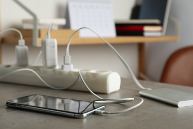 Devices charging with cable on light stone table