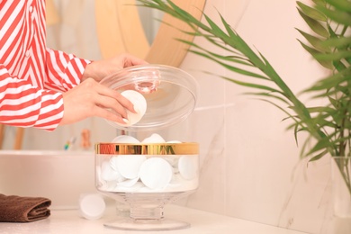 Photo of Woman taking cotton pad from jar in bathroom, closeup