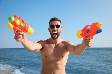 Man with water guns having fun on beach