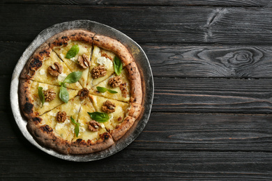 Photo of Delicious cheese pizza with walnuts on black wooden table, top view. Space for text