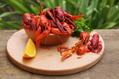 Photo of Delicious red boiled crayfish and orange on wooden table