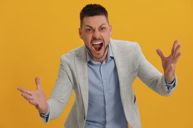Photo of Angry man yelling on yellow background. Hate concept