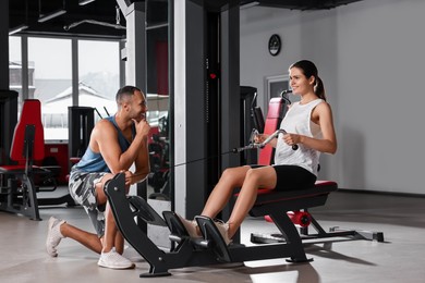 Photo of Happy trainer cheering up woman while she doing exercise in modern gym