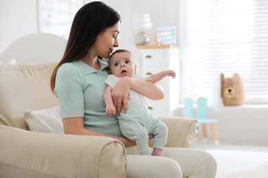 Young woman with her cute baby at home, space for text