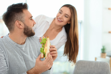 Photo of Happy couple having breakfast with sandwiches at home