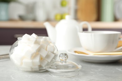 Photo of Glass bowl with white sugar cubes on grey table
