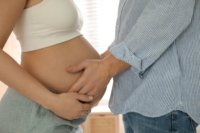 Photo of Man touching his pregnant wife's belly at home, closeup