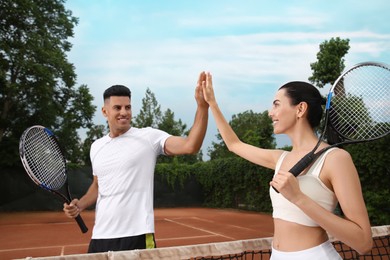 Woman giving man high five at tennis court