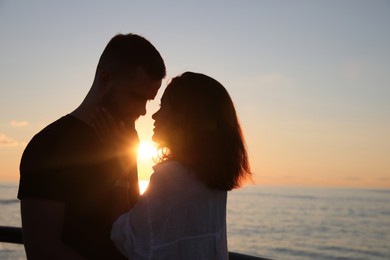 Happy young couple together near sea at sunset