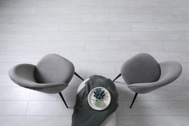 Stylish grey chairs and pouf with decor in room, top view. Interior design