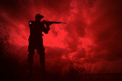 Image of Russian invasion of Ukraine. Silhouette of armed soldier from Russia outdoors, toned in red