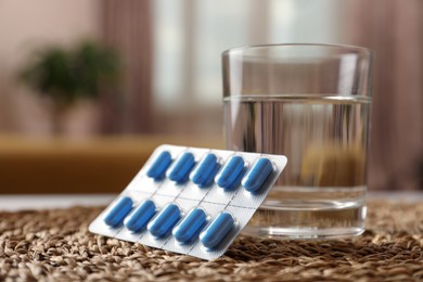 Photo of Glass of water and pills on wicker mat indoors, closeup. Potency problem concept