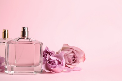 Bottles of perfume and beautiful roses on pink background. Space for text