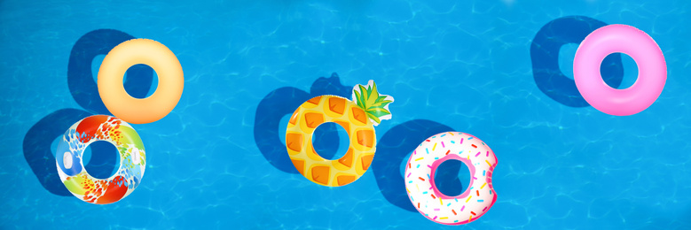 Different inflatable rings floating in swimming pool, top view. Banner design